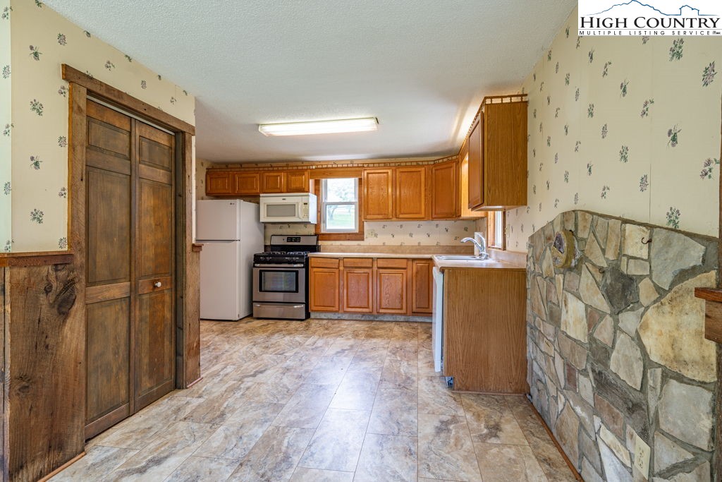 175 Roaring Fork Road Todd, NC 28684 - Photo 6 of 24 a kitchen with stainless steel appliances granite countertop a refrigerator sink and wooden cabinets