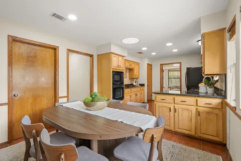 a kitchen with stainless steel appliances granite countertop a dining table chairs and couches