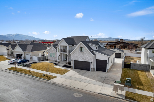 1426 South 1450th Street West Mapleton, UT 84664 - Photo 50 of 50 Modern residence featuring a light-colored brick and white siding exterior, dark shingles, and a two-car garage