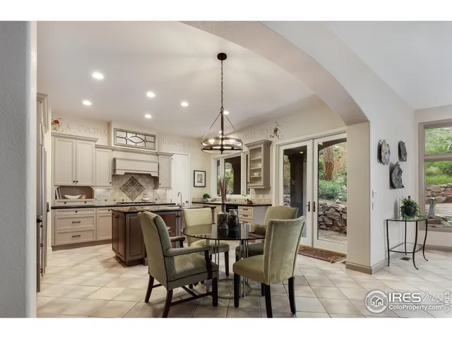 a kitchen with stainless steel appliances kitchen island granite countertop a dining table chairs and white cabinets