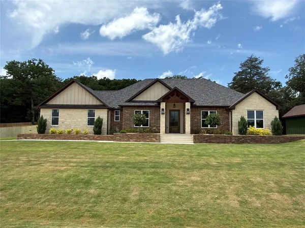 a front view of a house with a garden and trees
