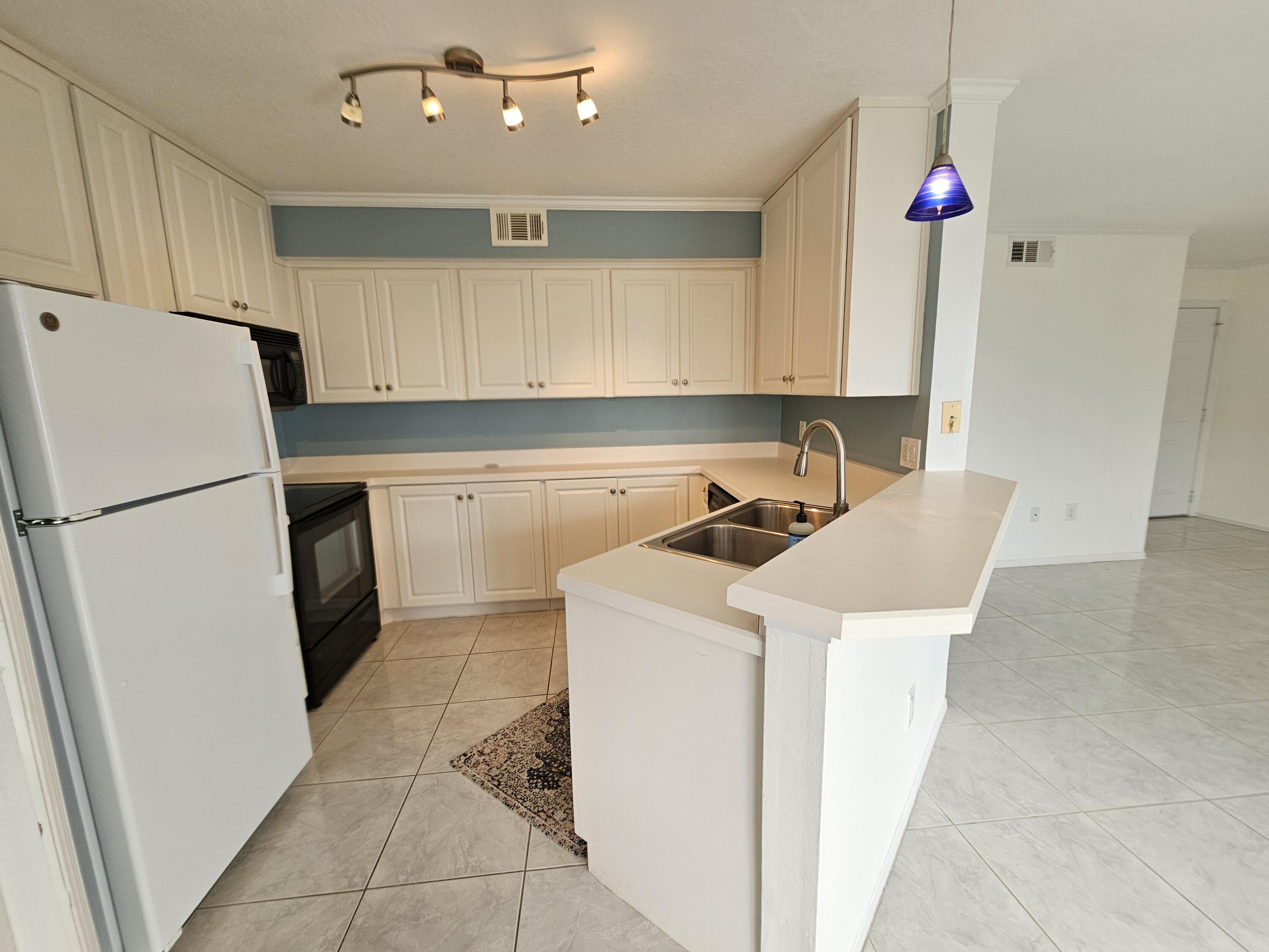7330 N Highway, Unit 102 Cocoa, FL 32922 - Photo 9 of 26 a kitchen with a sink a refrigerator a stove and cabinets