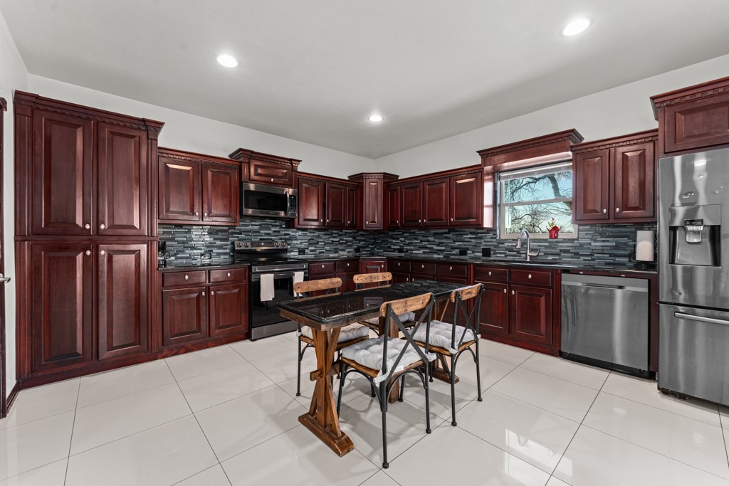 1206 Walter Hoffman Road Cedar Creek, TX 78612 - Photo 21 of 40 a kitchen with stainless steel appliances granite countertop wooden cabinets a stove a sink and a microwave