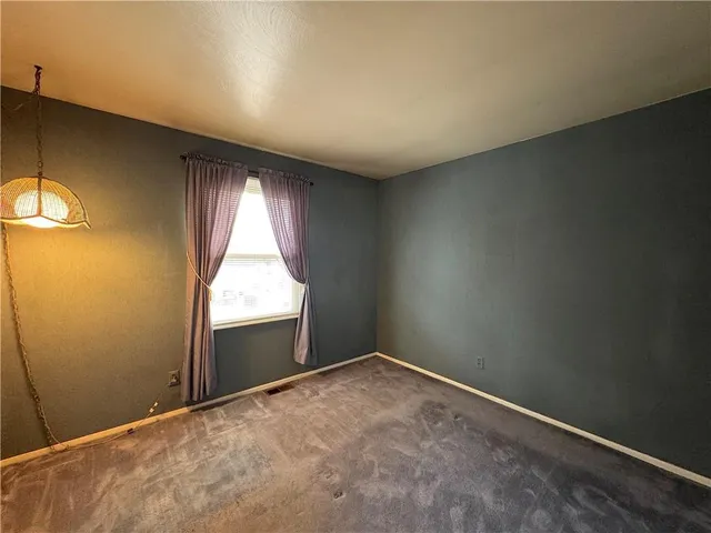an empty room with a fireplace and windows