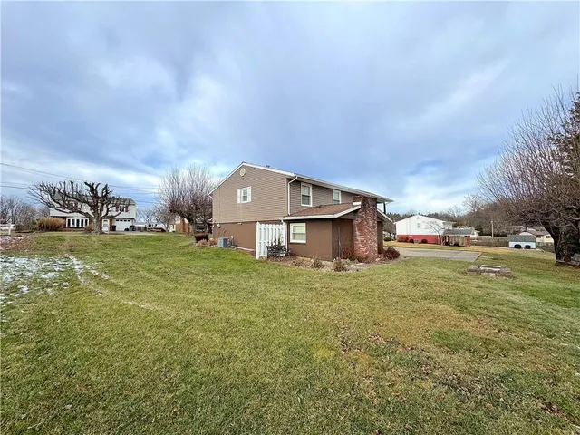 a yellow and red house sitting in the middle of a big yard