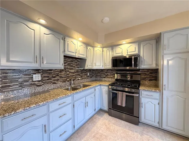 a kitchen with sink a microwave a stove and cabinets