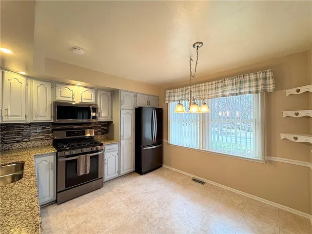 a kitchen with stainless steel appliances granite countertop a refrigerator a stove a sink and a microwave