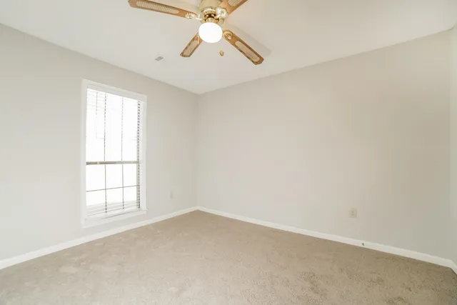 an empty room with windows and fan