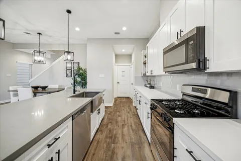 a kitchen with stainless steel appliances granite countertop a sink a stove and a wooden floors