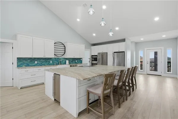 a kitchen with stainless steel appliances kitchen island granite countertop a stove a sink and a refrigerator