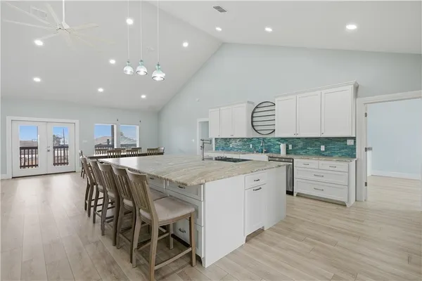 a large kitchen with granite countertop a large counter top and stainless steel appliances