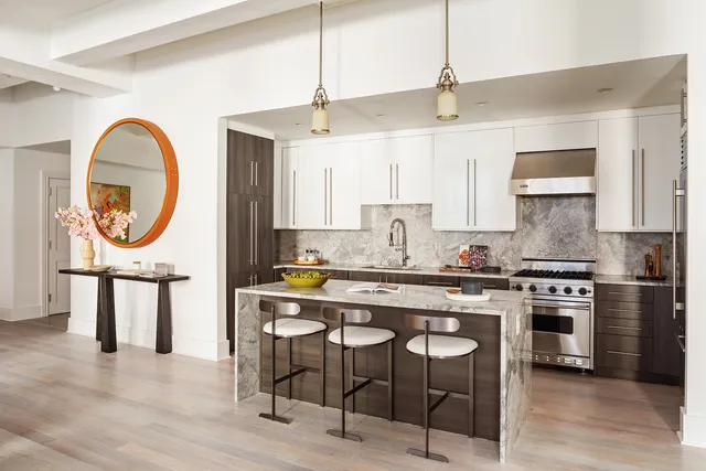 a kitchen with a stove a chandelier and white cabinets