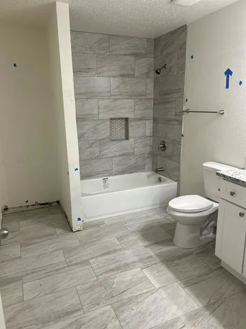 a bathroom with a granite countertop toilet a sink and a mirror