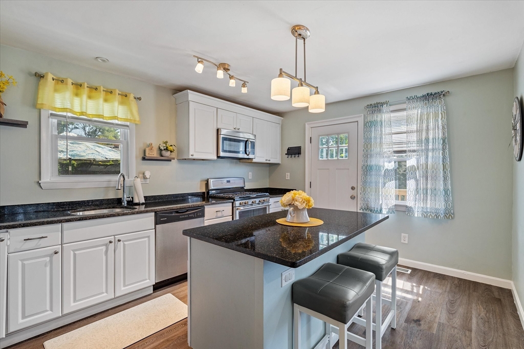 14 Grosvenor Street Ayer, MA 01432 - Photo 10 of 30 a kitchen with stainless steel appliances granite countertop a stove a sink a dining table and chairs with wooden floor