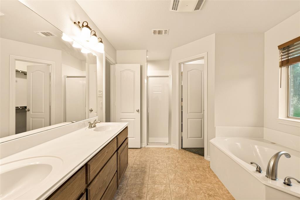 2105 Ridgewood Drive Bridgeport, TX 76426 - Photo 19 of 27 Bathroom featuring a double vanity with wood-finish cabinetry, a large soaking tub, and a separate shower enclosure