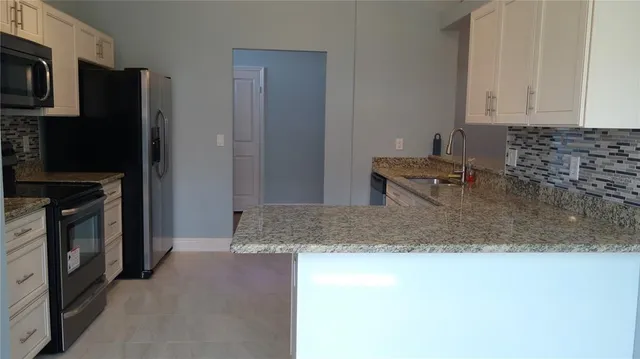 a kitchen with stainless steel appliances granite countertop a refrigerator a stove and a sink