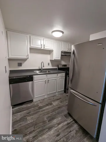 a kitchen with stainless steel appliances a sink a stove a refrigerator and cabinets