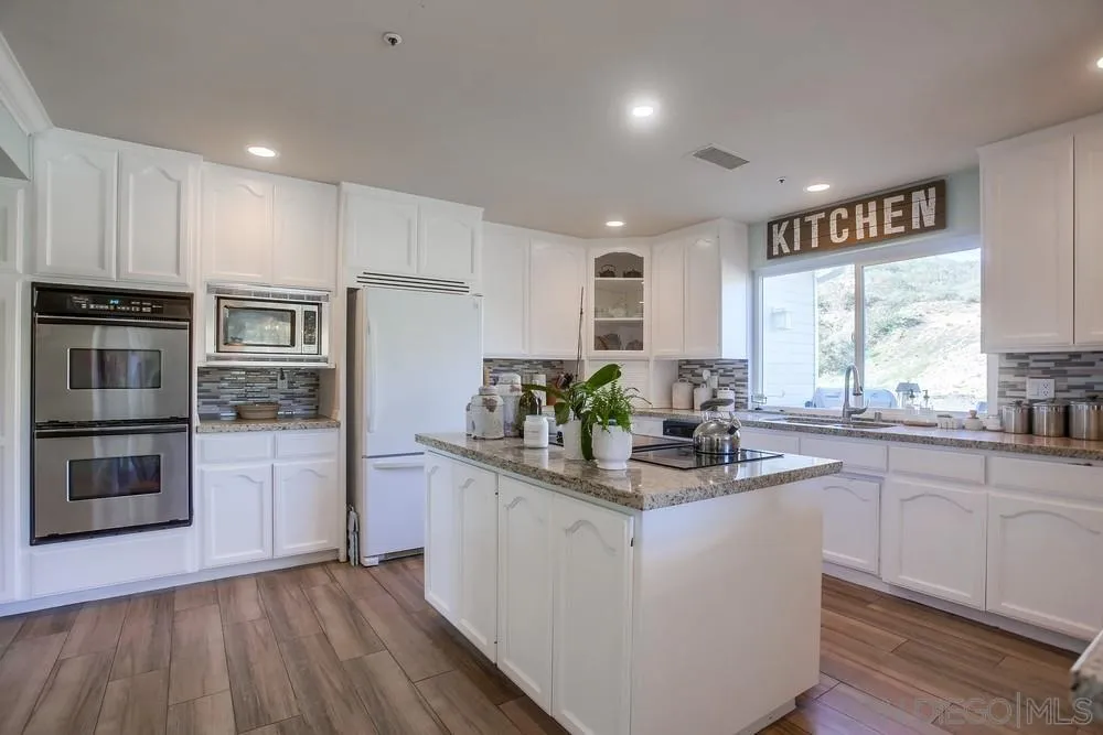 39221 Daily Road Fallbrook, CA 92028 - Photo 10 of 26 a kitchen with stainless steel appliances granite countertop a refrigerator a stove top oven a sink and dishwasher with wooden floor