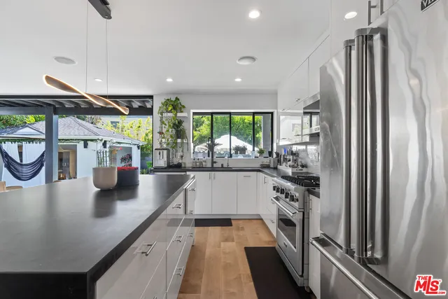 a kitchen with stainless steel appliances granite countertop a refrigerator a sink and a stove