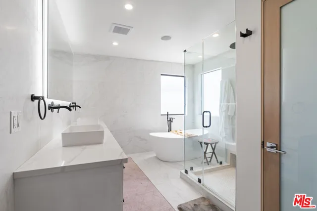 a bathroom with a double vanity sink a mirror and a bathtub