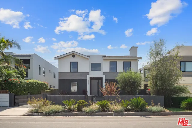 a front view of a house with plants and trees