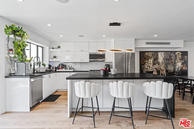 a kitchen with stainless steel appliances granite countertop a table chairs refrigerator and sink