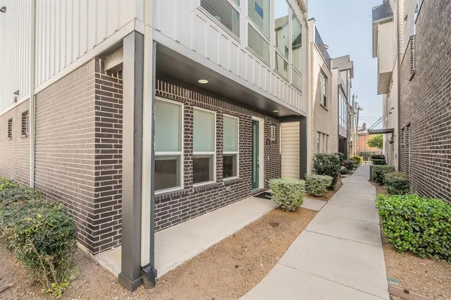 a view of a brick house with a large windows and plants