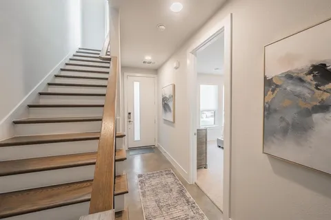 a view of a hallway with stairs and wooden floor