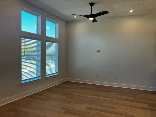 en empty room with wooden floor fan and windows