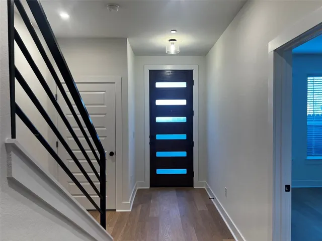 an entryway in a hallway with wooden floor and stairs