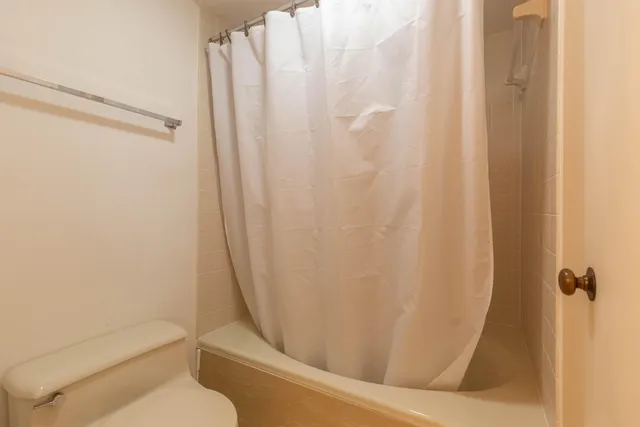 a bathroom with a toilet and a shower curtain