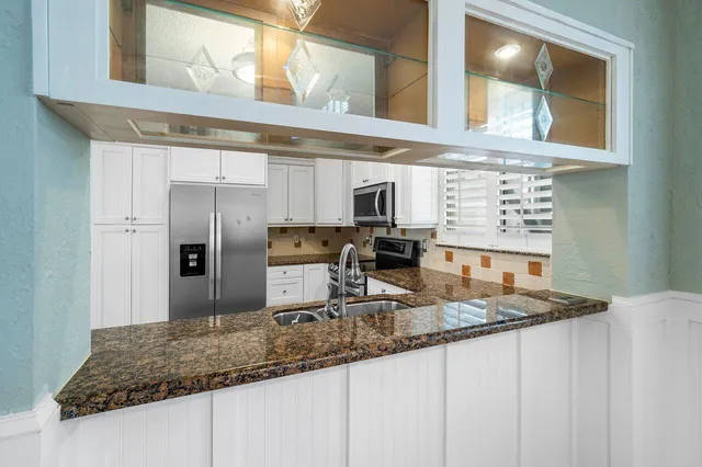 a kitchen with granite countertop a sink a stove and refrigerator