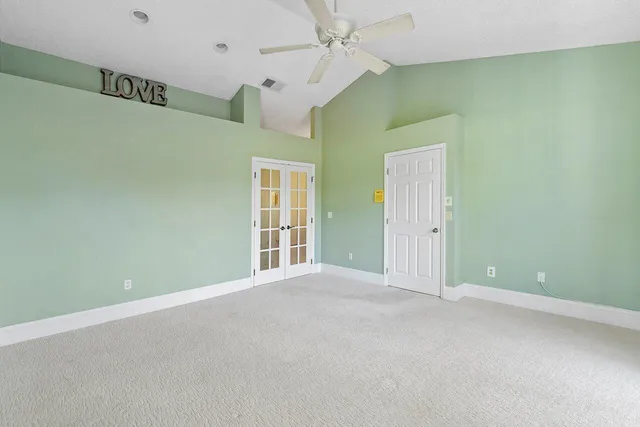 an empty room with ceiling fan and windows