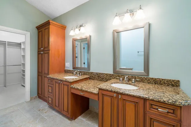 a bathroom with a granite countertop double vanity sink and a mirror