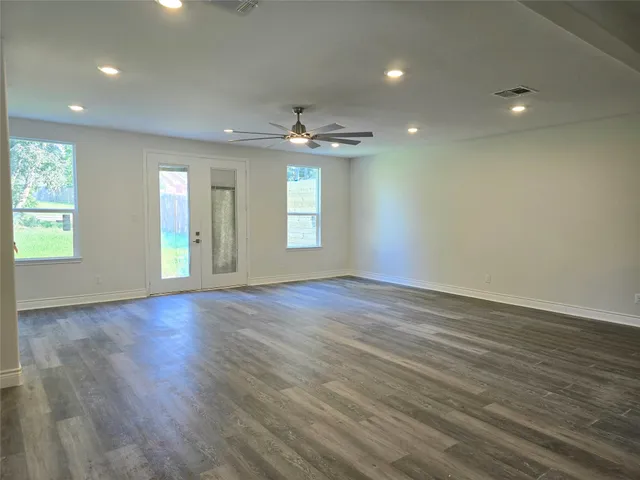 an empty room with wooden floor and windows
