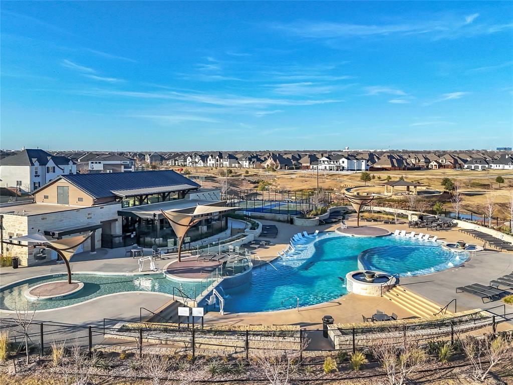 1011 Prairie Ridge Lane Arlington, TX 76005 - Photo 5 of 32 Community clubhouse featuring a metal roof and stone accents, with an expansive swimming pool complex