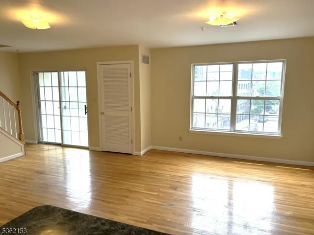 a view of an empty room with window wooden floor and a kitchen