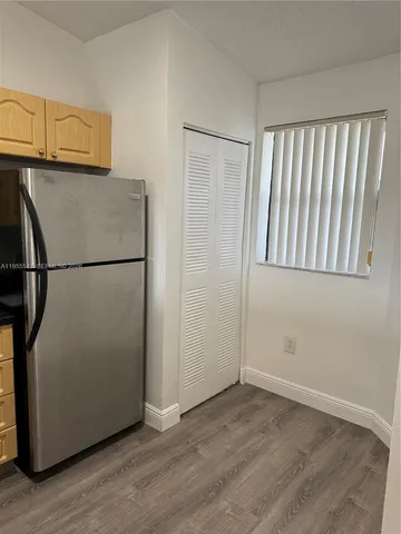 a view of a refrigerator in kitchen and an empty room