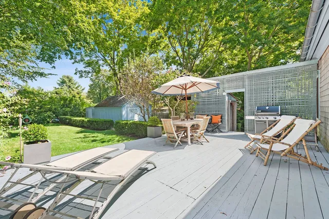 a view of a patio with table and chairs under an umbrella with wooden floor and fence
