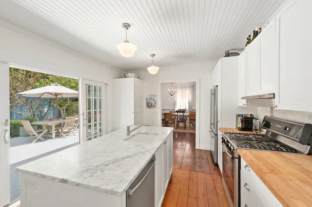 a kitchen with granite countertop a stove a sink a refrigerator and wooden floor