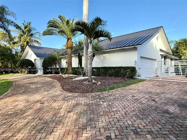 a view of a house with a yard and palm trees