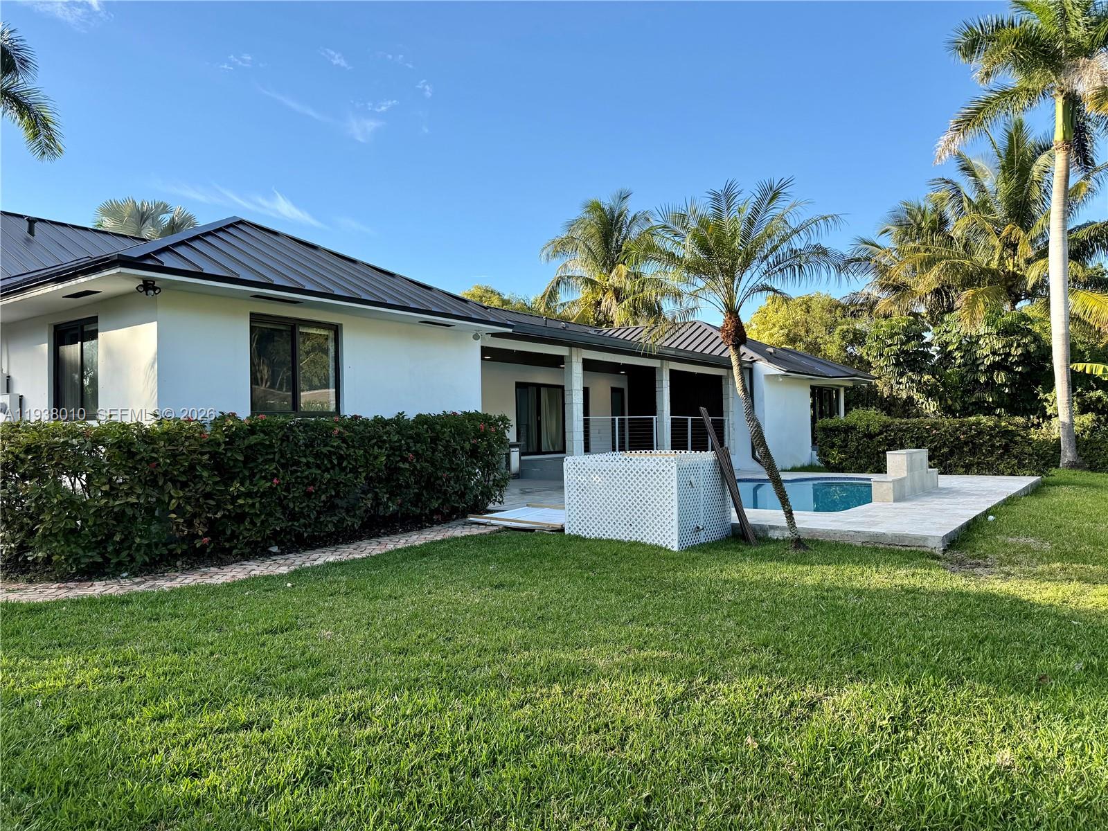 13407 Southwest 59th Avenue Pinecrest, FL 33156 - Photo 48 of 50 a front view of a house with a yard and garage