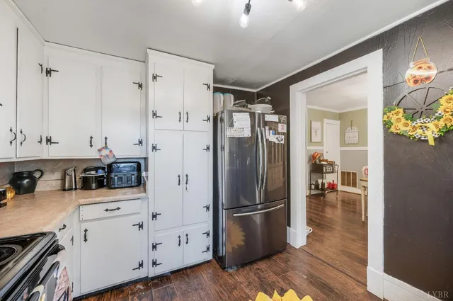 a kitchen with a refrigerator a stove and white cabinets
