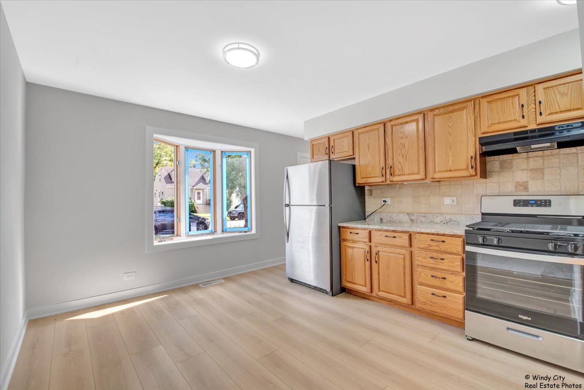 14914 Avers Avenue Midlothian, IL 60445 - Photo 5 of 22 a kitchen with stainless steel appliances granite countertop a stove top oven a refrigerator a sink and dishwasher with wooden floor