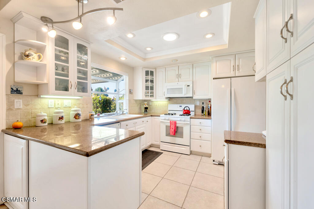 4331 Mill Valley Road Moorpark, CA 93021 - Photo 10 of 40 a kitchen with a sink a stove a refrigerator and white cabinets with wooden floor
