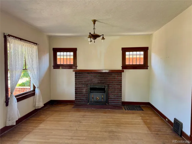 wooden floor fireplace and windows in an empty room