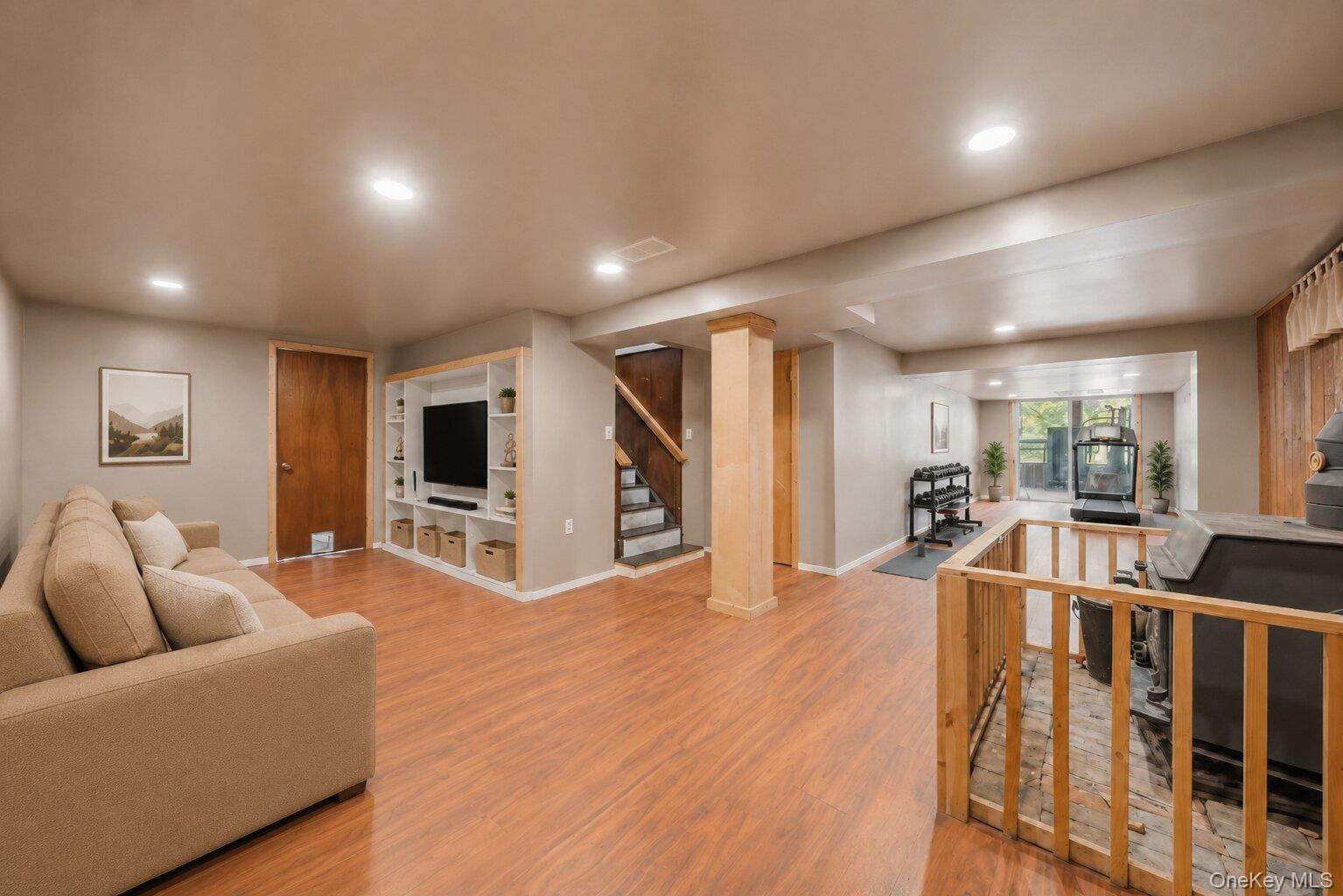 49 Chase Road Wallkill, NY 12589 - Photo 18 of 32 Virtually Staged. Finished lower-level space featuring wood-look flooring, recessed lighting, a brick chimney with a supplemental stove, and room for exercise equipment or hobbies.