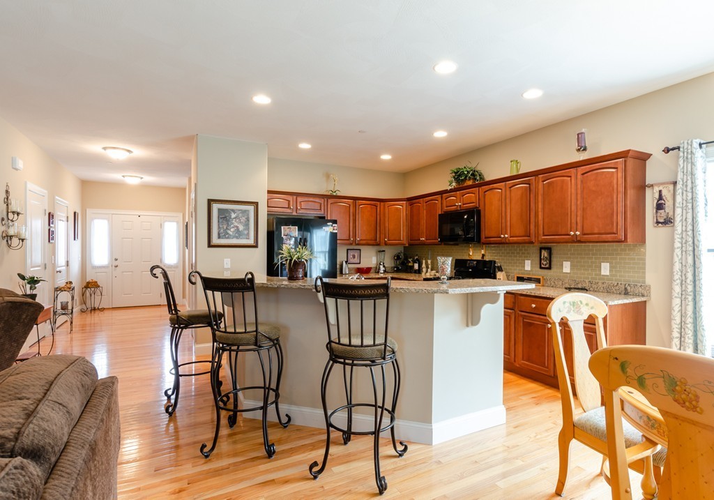2 Thorn Hill Road, Unit 2 Hooksett, NH 03106 - Photo 11 of 27 a kitchen with stainless steel appliances kitchen island granite countertop dining room cabinets and wooden floor