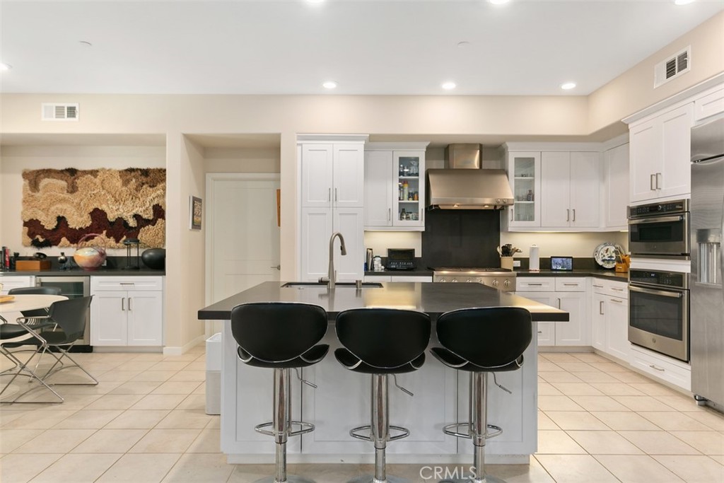 229 Carlow Irvine, CA 92618 - Photo 2 of 32 a kitchen with stainless steel appliances granite countertop a stove top oven a sink a dining table and chairs with white cabinets