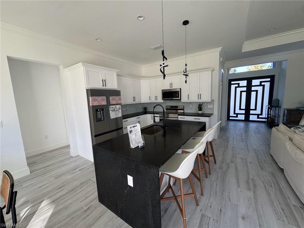 308 Golden Gate Boulevard East Naples, FL 34117 - Photo 11 of 29 a kitchen with stainless steel appliances granite countertop a stove a refrigerator a kitchen island a hardwood floor and a sink